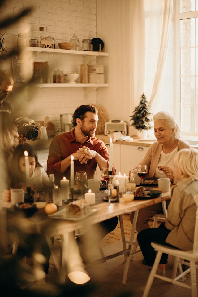 This is a picture of a mand, his daughter, and son sitting at a table eating with his mother. Signifying family Unity